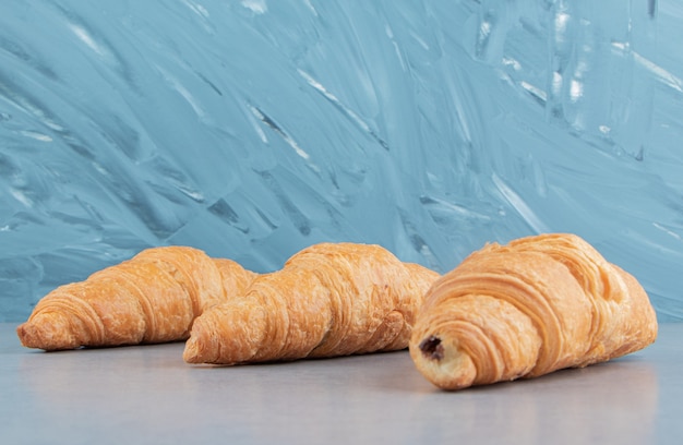 Three flavorful croissant , on the blue background . High quality photo