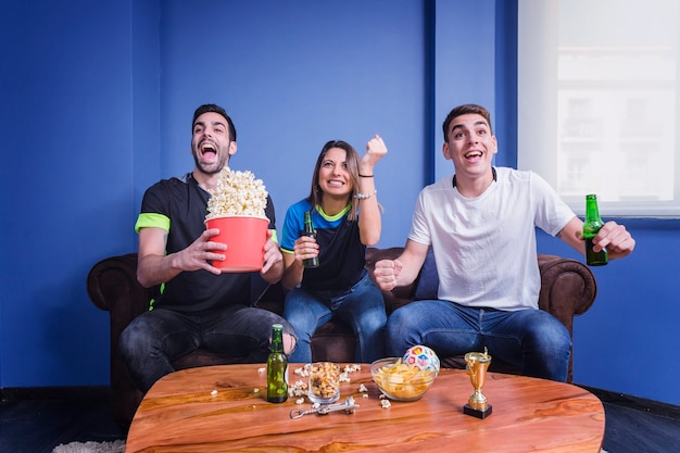 Three football fans celebrating in living room