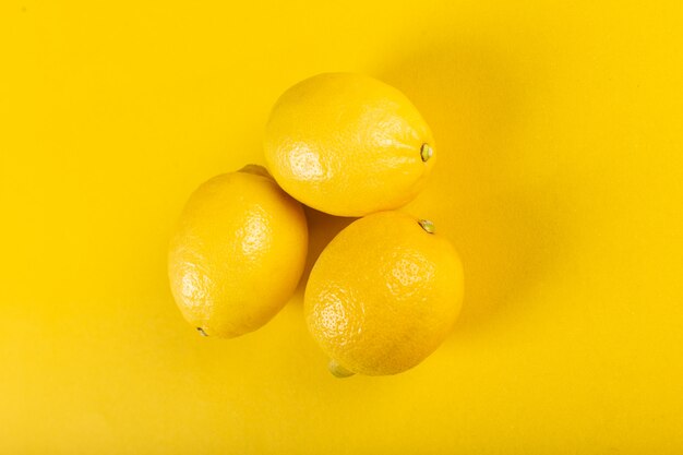 Three fresh bright lemons on yellow