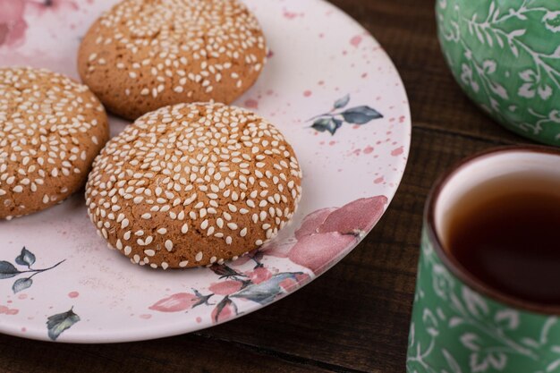 Three fresh cookies with cup of tea on wooden table.