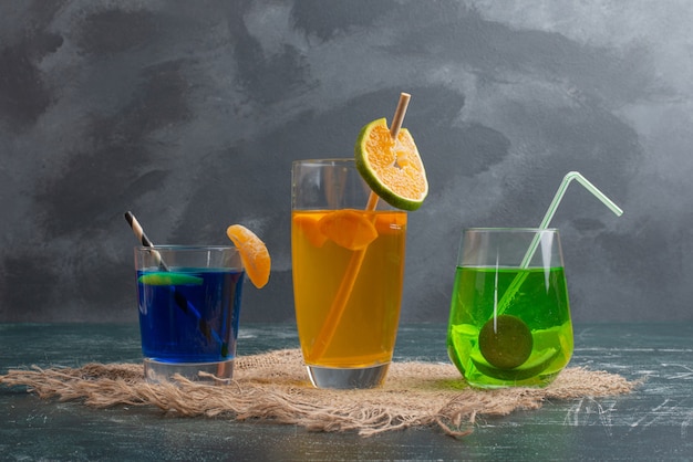 Three fresh drinks on marble table .