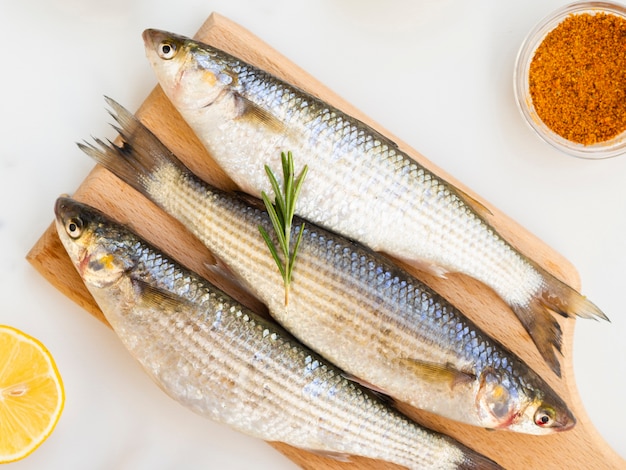 Three fresh fish on wooden bottom with condiments