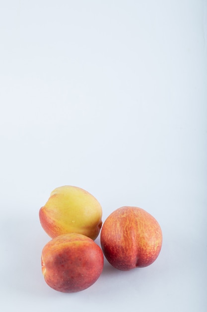 Three fresh nectarines on white.