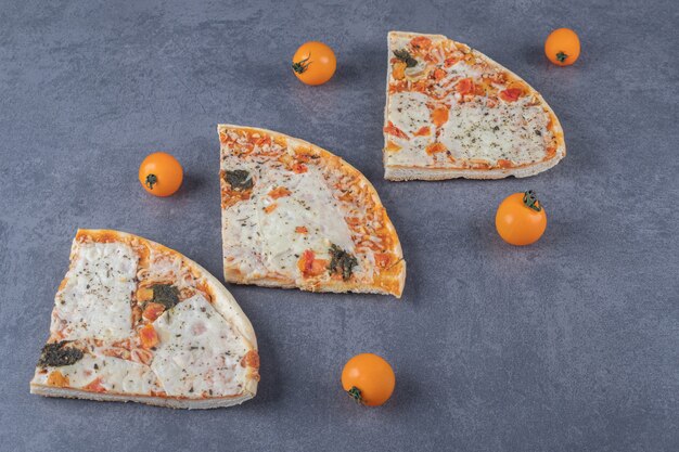 Three fresh pizza slice on grey background.