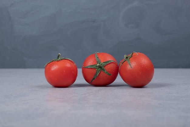 Three fresh tomatoes on gray background. High quality photo