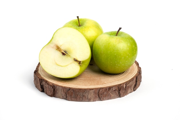 Три свежих целых и нарезанных яблока на деревянном куске.