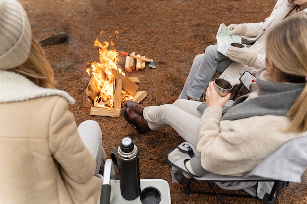 Three friends drinking water and sitting by a bonfire