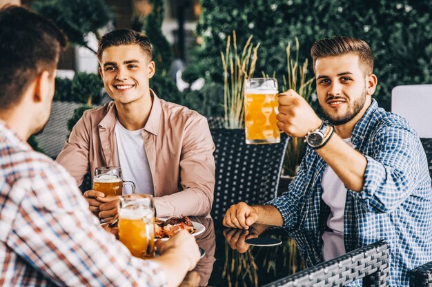 カフェで食事をし、ビールを飲む3人の友人