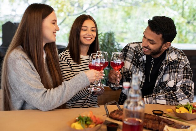 Three friends at a get-together cheering with glasses of wine