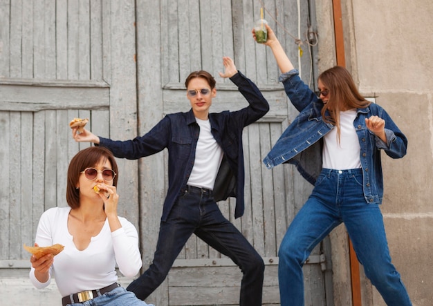 Free photo three friends having fun outdoors while eating burger