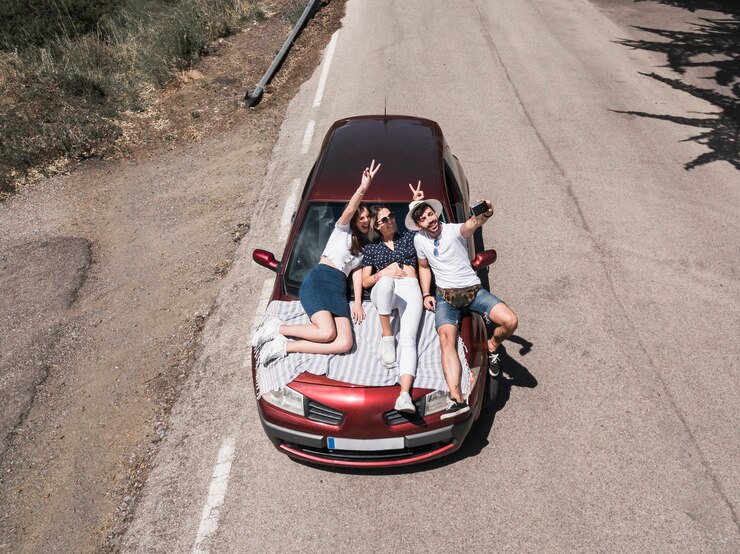無料Photo 自画像を撮っている車のフードに座っている3人の友人