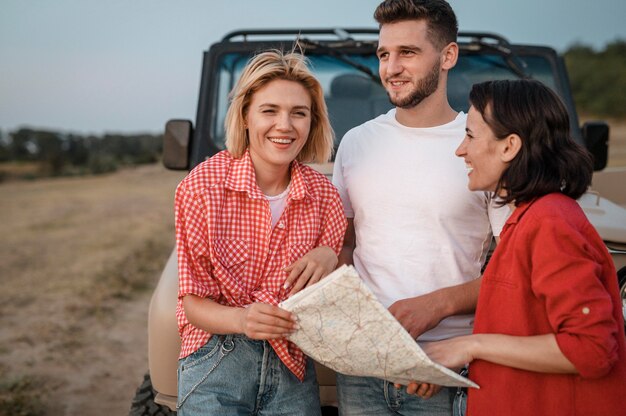 Three friends traveling by car and checking map