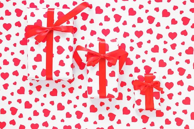 Three gift boxes with red ribbons on table