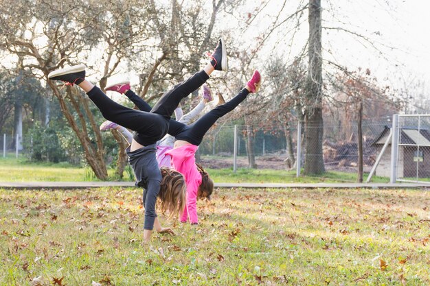 Three girls doing handstand exercising in the park