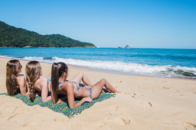 Three girls lying on the sand