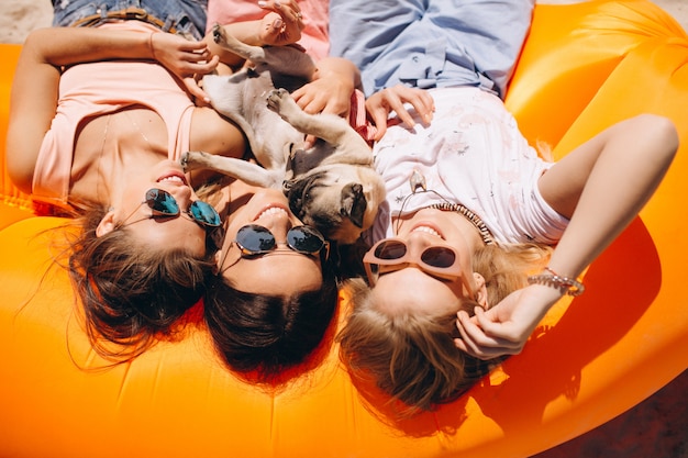 Free photo three girls with small dog lying on pool mattress at the beach