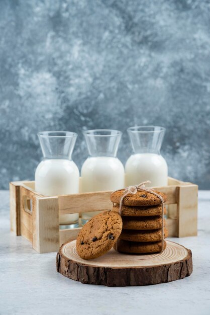 Three glass jar of milk and stack of cookies on marble table.