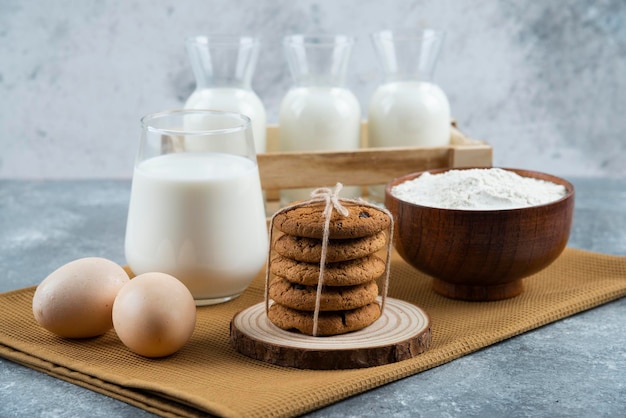 Three glasses of milk with flour and eggs on a gray table.