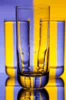 Foto gratuita tre bicchieri con acqua su viola e giallo