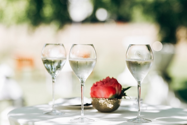 Three glasses with water and red peony stand on the table