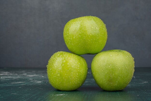 Three green apples on marble surface