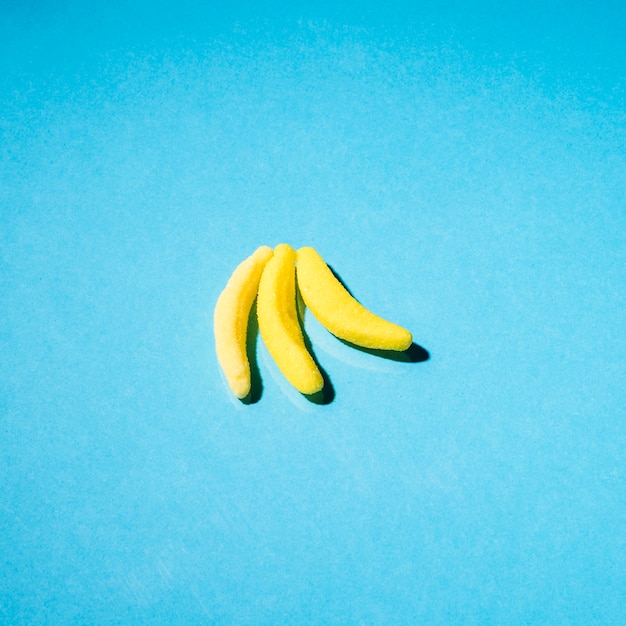 Three gummy banana candies on blue backdrop