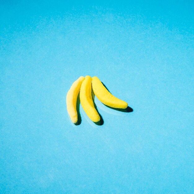 青い背景に3つのグミのバナナのキャンディー