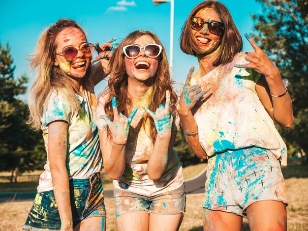 Три счастливые красивые девушки устраивают вечеринку на фестивале красок Холи