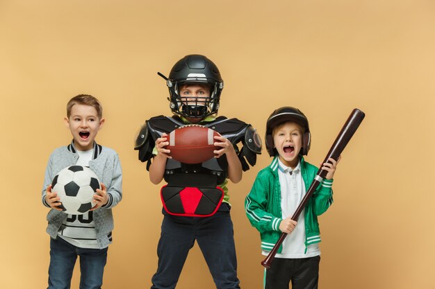 3人の幸せな子供たちはさまざまなスポーツ衣装を見せて