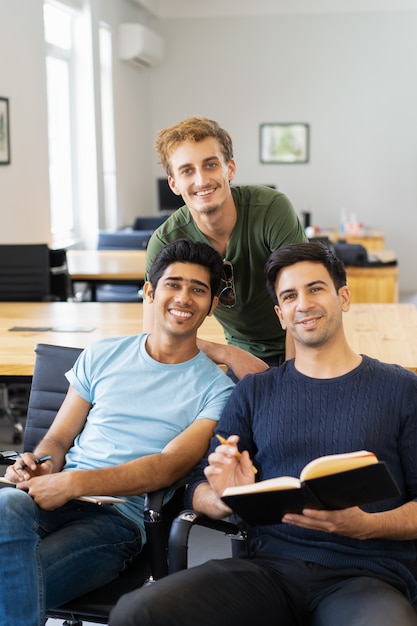 勉強してカメラを見ている3人の幸せな仲間の学生