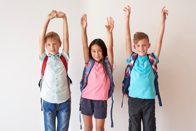 Three happy kids raising hands