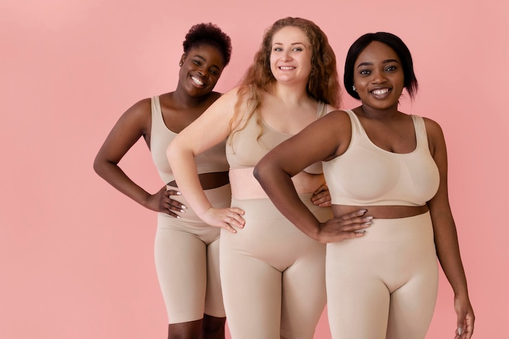Free Photo three happy women posing while wearing a body shaper