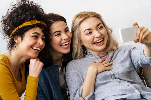 Three happy women smiling and taking a selfie