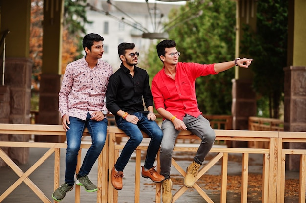 Three indian guys students friends posed on street one of men show finger