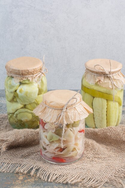 Three jars full of salty vegetables on sackcloth