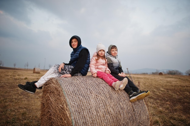 Three kids sitting on haycock at field