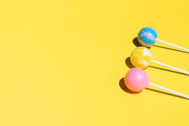 Three lollipops on yellow table