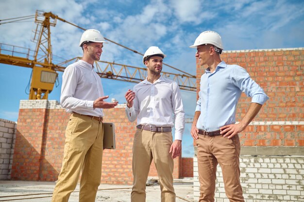 Трое мужчин общаются на строительной площадке