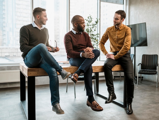 Foto gratuita tre uomini che conversano in ufficio durante una riunione