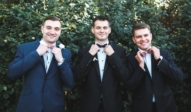 Free photo three men in suits posing in garden