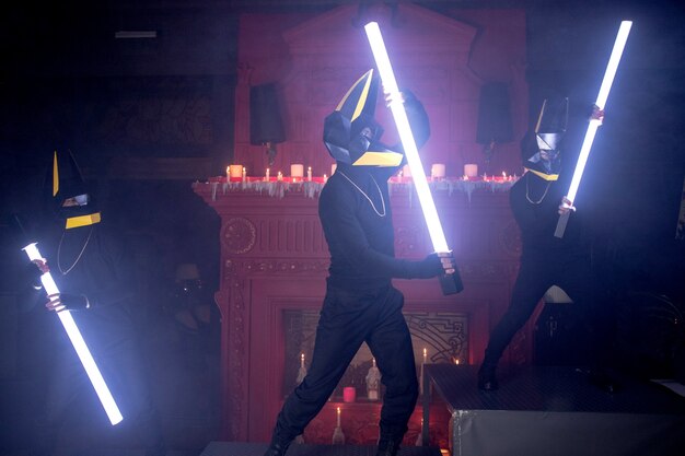 Three men in wolf masks dance with light bulbs in the club