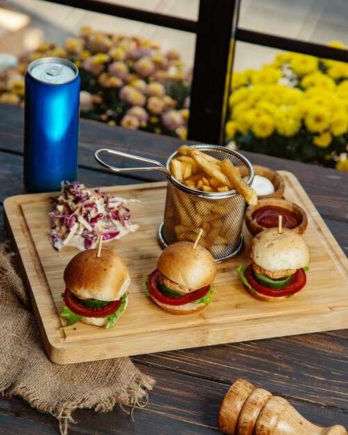 Three mini chicken burgers served with french fries coleslaw mayonnaise and ketchup