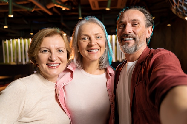 Free photo three older friends taking a selfie at a restaurant