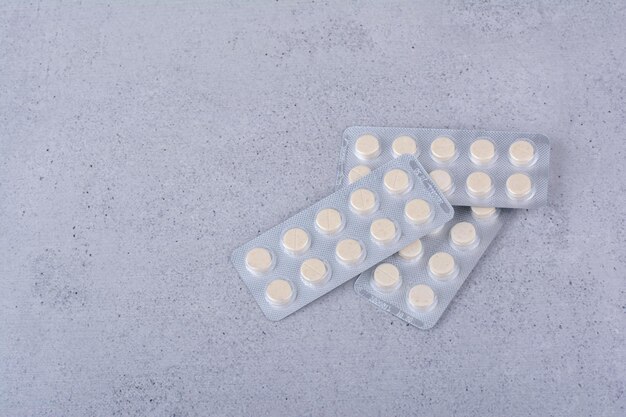 Три упаковки круглых таблеток медицины на мраморном фоне. Фото высокого качества