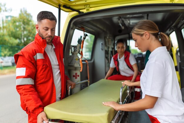 Three paramedics taking out strecher from ambulance