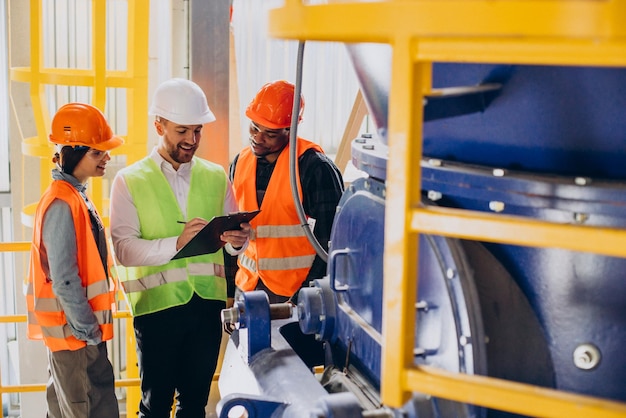 Three people discussing a plan at a factory