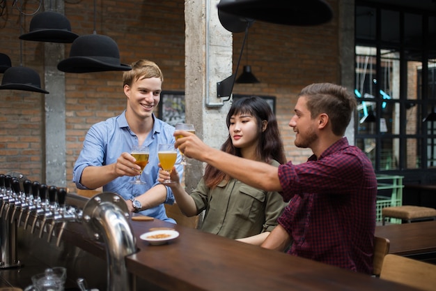 Foto gratuita tre persone tostare e bere birra nel pub