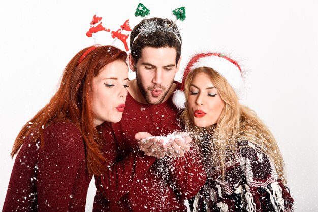 Три человека в шляпе Санта дует снежинки из их рук