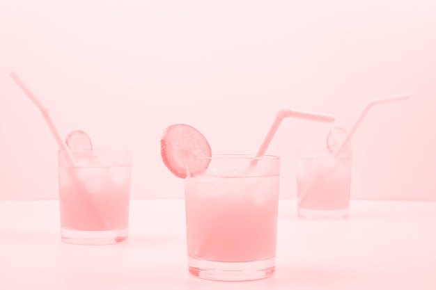 Three pink cocktail glasses on colored background