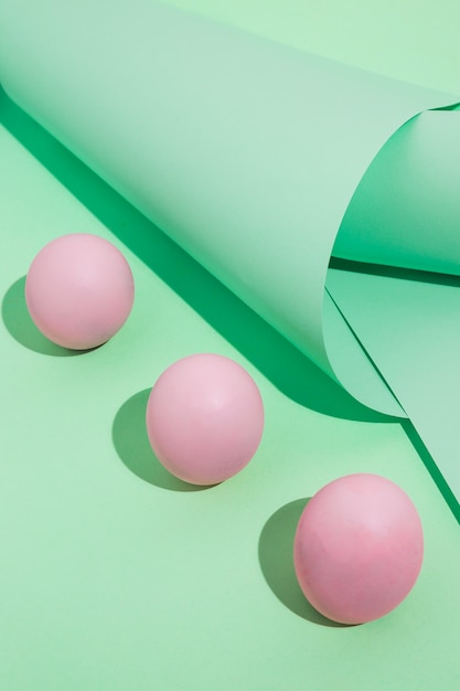 Free photo three pink easter eggs with green rolled paper